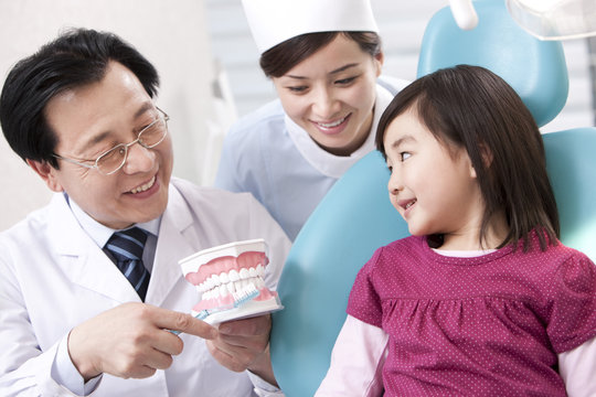 Dentist teaching the right way of brushing teeth