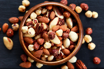 mix nuts in wooden bowls on old blue stone background.
