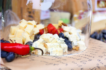 Cheese and berries under glass bowl on table