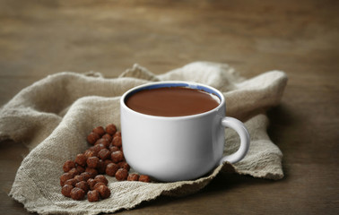 Cup of cacao with sweets and napkin on wooden table