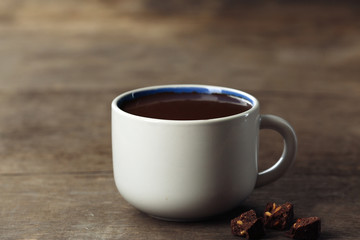 Cup of cacao with chocolate on wooden background