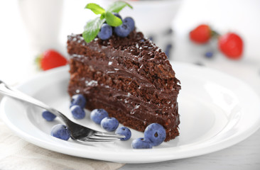 Chocolate cake with chocolate cream and fresh berries on plate, on wooden background