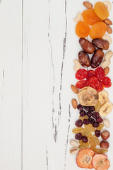 Mix of dried fruits and nuts on a white vintage wood background with copy space. Top view. Symbols of judaic holiday Tu Bishvat