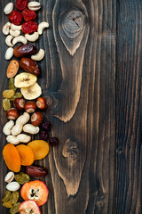 Mix of dried fruits and nuts on a dark wood background with copy space. Top view. Symbols of judaic holiday Tu Bishvat