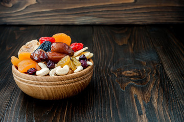 Mix of dried fruits and nuts on dark wood background with copy space. Symbols of judaic holiday Tu Bishvat