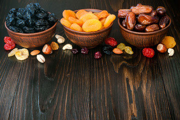 Mix of dried fruits and nuts on dark wood background with copy space. Symbols of judaic holiday Tu Bishvat