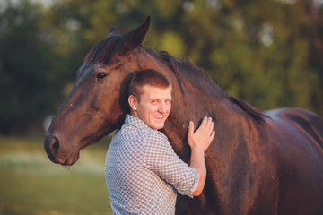 Young man hugs a horse