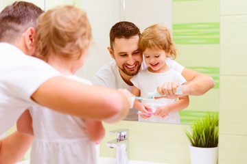 Fototapeta premium Happy family father and child girl brushing her teeth in bathroo