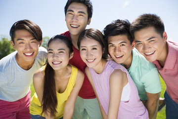 Group photo of cheerful young adults standing on grass