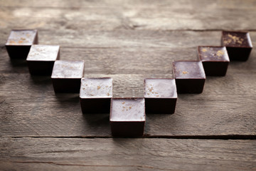 Tasty chocolate candies on wooden background. V-shaped