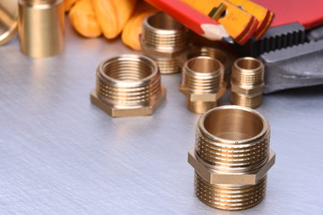 Parts of plumbing fitting with wrench and tools on metal surface