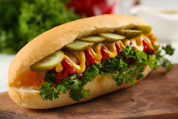 Delicious hot-dog with tomatoes  on wooden chopping board, close up
