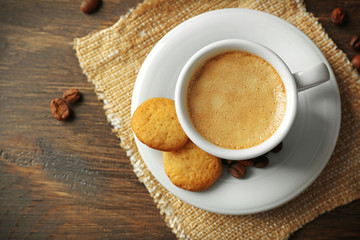 Cup of coffee on sackcloth napkin, on wooden table background