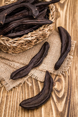 Dried Carob Pods, Ceratonia Siliqua on wooden table	