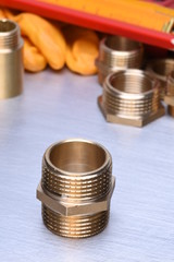 Parts of plumbing fitting with wrench and tools on metal surface