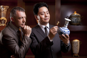 Mature businessmen admiring an antique Chinese vase