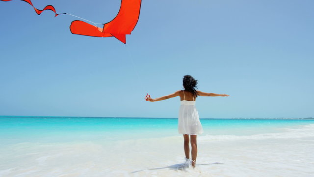 Smiling African American girl playing with a red kite on beach 