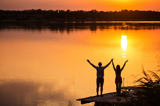 couple in love back light silhouette at lake sunset 