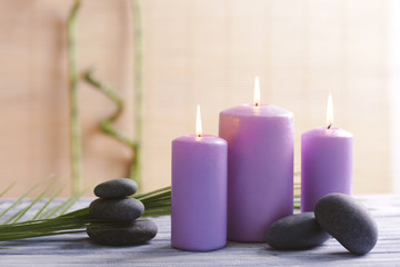 Purple candles with spa stones and bamboo on table