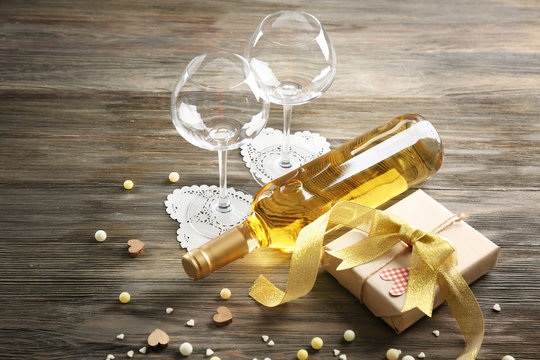 Love concept - wine bottle and gift on wooden background, close up