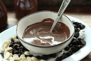 Melted chocolate in bowl, on wooden background