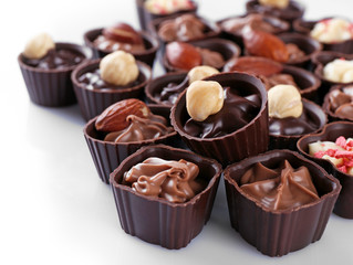 Delicious chocolate candies on white background, close up