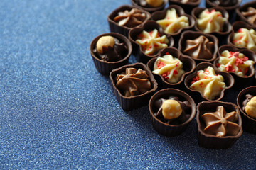 Delicious chocolate candies on blue background, close up