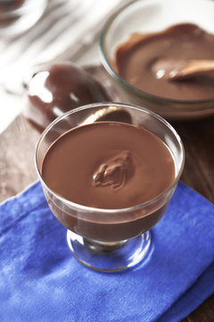 Melted chocolate in glass bowl, on wooden background