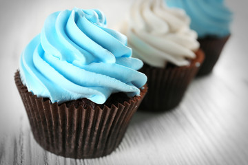 Fresh delicious cupcakes in a row on white wooden  background