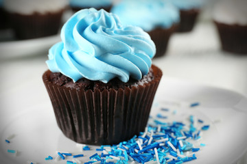 Delicious chocolate cupcake with blue cream on decorated wooden  table, close up