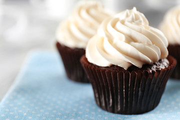 Delicious chocolate cupcakes with cream on served table, close up