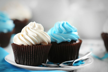 Chocolate cupcakes with colourful cream on served table, close up
