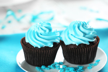 Delicious chocolate cupcakes with blue cream on decorated wooden  table, close up