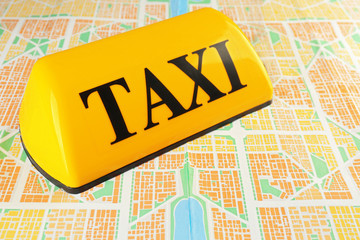 Transportation concept. Yellow taxi sign on city map, close up