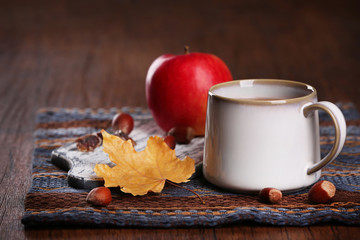 Cup of tea with autumn decor on wooden table.
