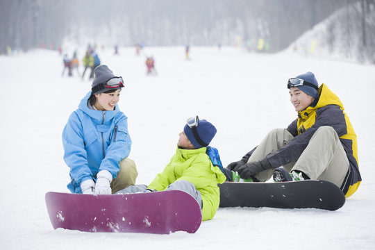 Young parents teaching son to snowboard