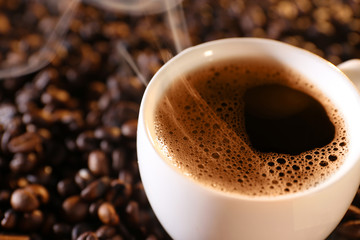 Cup of hot coffee on coffee beans background