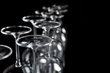 Wine glasses in a row upside down on black background