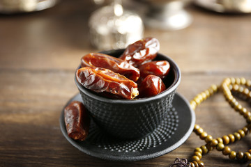 Dates fruit and rosary on served wooden background, close up