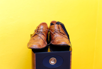 groom brown wedding shoes on speaker. Yellow background.