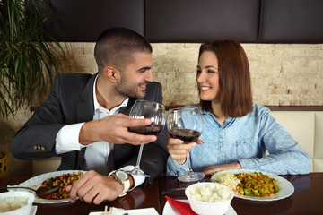 Happy young couple in love toasting to their relationship while having a dinner at the restaurant