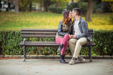 Beautiful couple kissing while sitting on a park bench