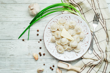 Russian national cuisine , cooked dumplings with meat, spices , green onions, pepper, salt and butter on a wooden background