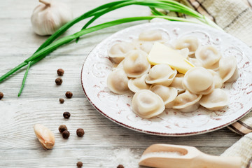 Russian national cuisine , cooked dumplings with meat, spices , green onions, pepper, salt and butter on a wooden background