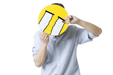 Young man with a crying emoticon face in front of his face