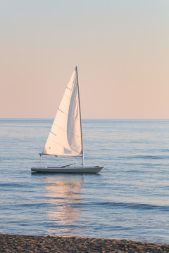 small sailboat in the water anchored next to the beach