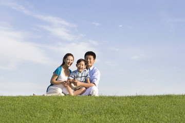 Fototapeta premium Family of three sitting on the grass