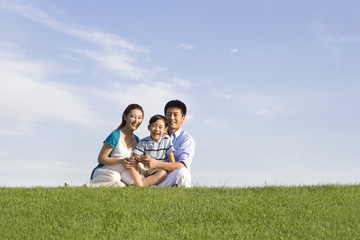 Family of three sitting on the grass