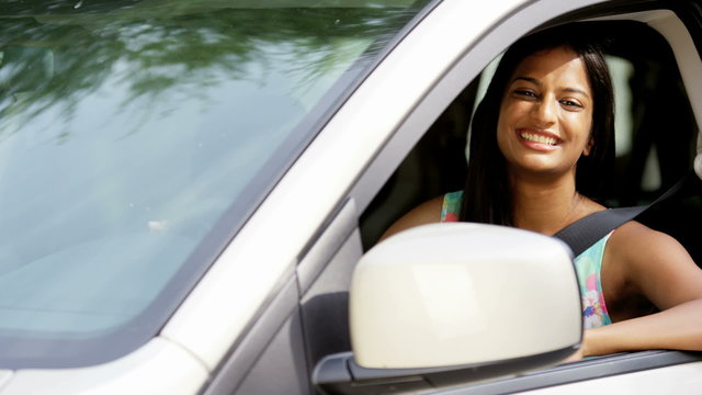 Portrait of young pretty Indian Asian girl driving new vehicle