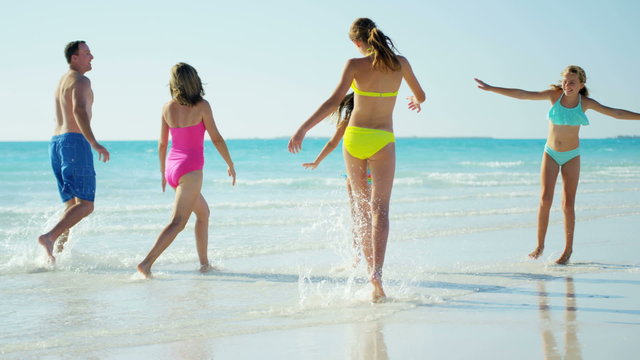 Caucasian family wearing colorful swimwear barefoot on beach